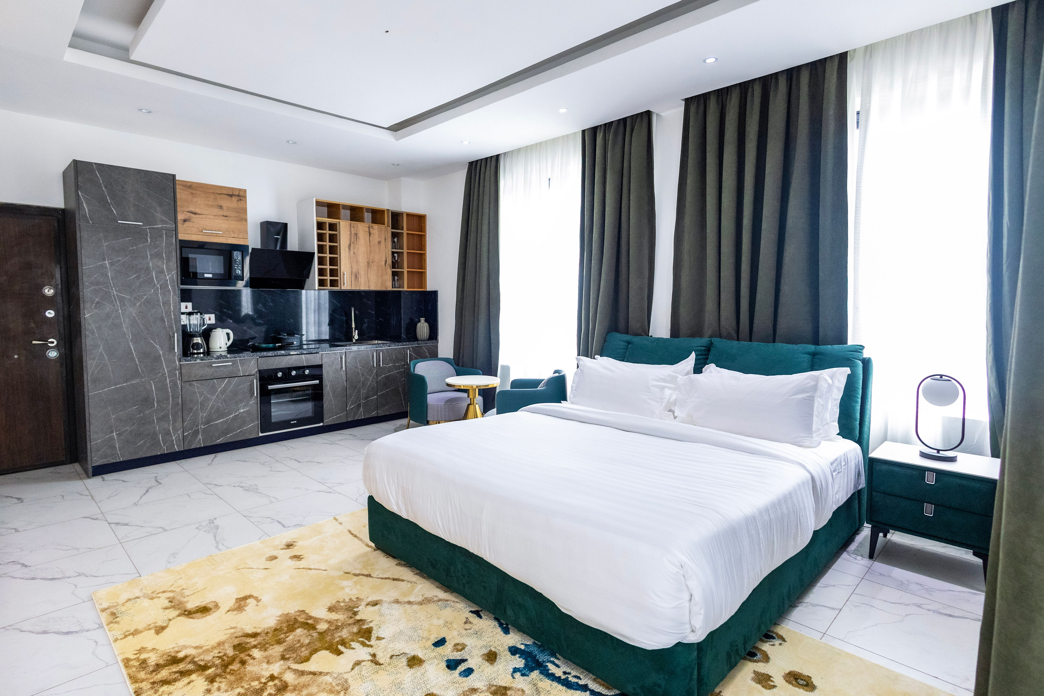Executive Studio with the teal bed, fitted kitchen and seating in one room